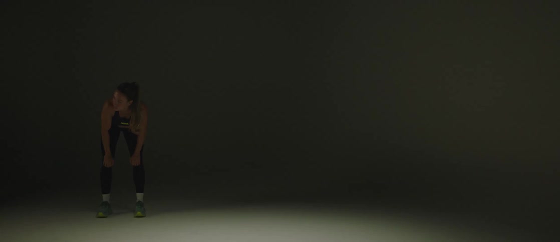 Lady in a track wear with head bent forward in a dark room