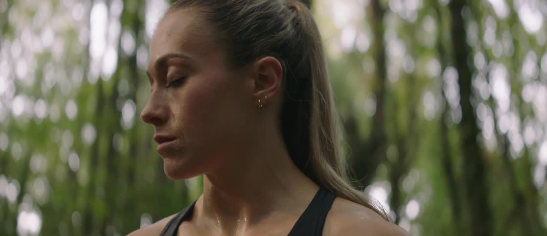 A woman standing still and with droopy eyes is all sweaty