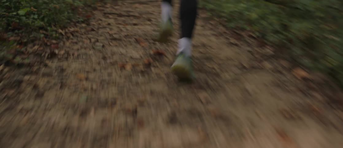 A woman is running on a trail in the woods