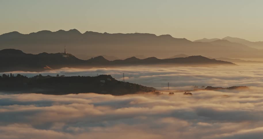An aerial shot of fog and clouds covering the Hollywood Hills in dawn light