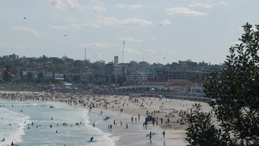 A beach filled with people close to a city