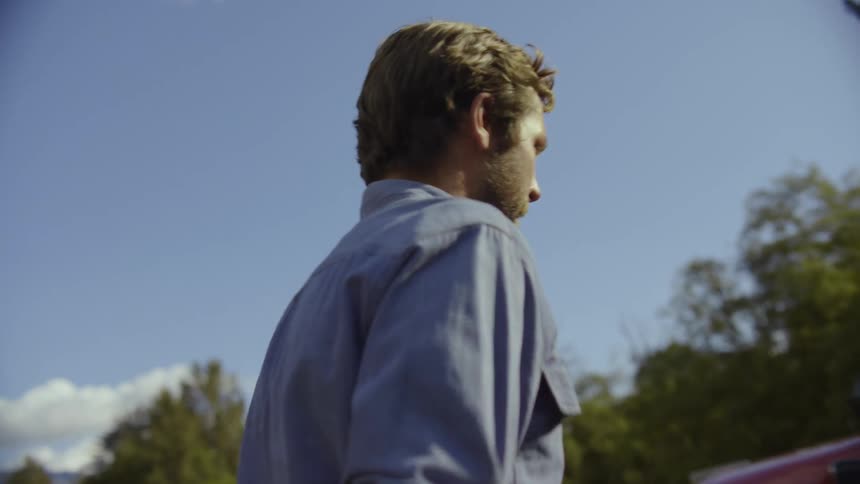 An adult man walks and then gets into an old red farm truck