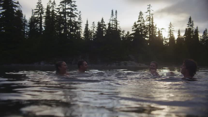 A group of friends bathing in the river at sunset