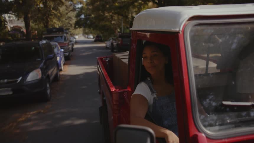 Female In the passenger seat of a moving red pickup truck during the day