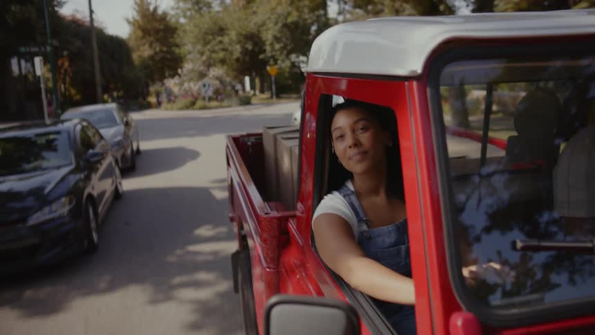 A woman looking out the window of a pickup truck admiring the streets of a charming neighborhood