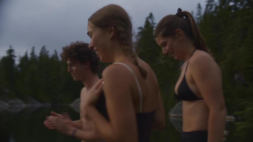 Friends jumping on the shore of a lake