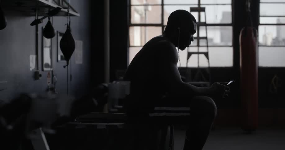 A man is sitting in a gym using a phone