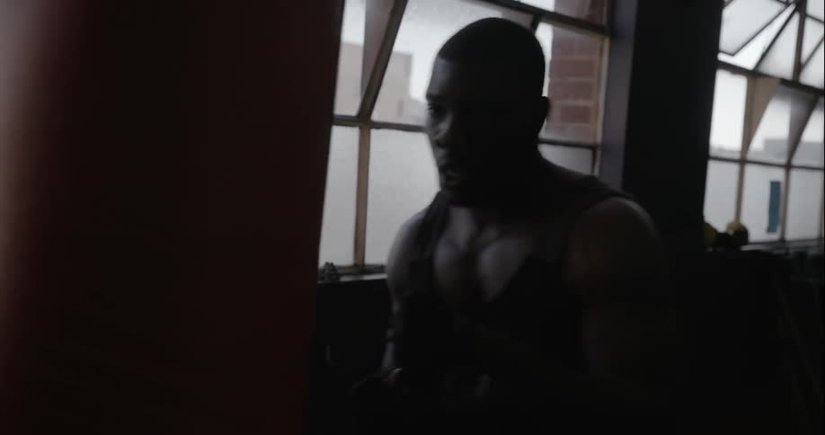 A man wraps his hands and punches a heavy bag