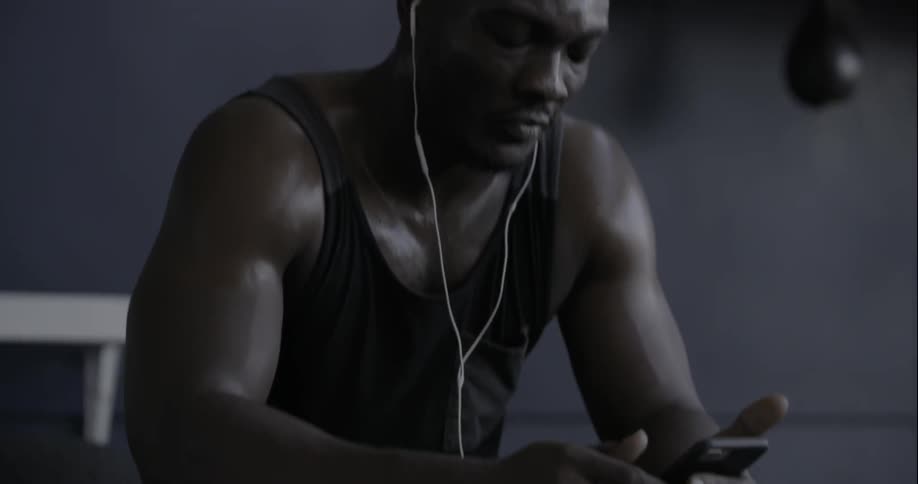A man is sitting down listening to music on his phone