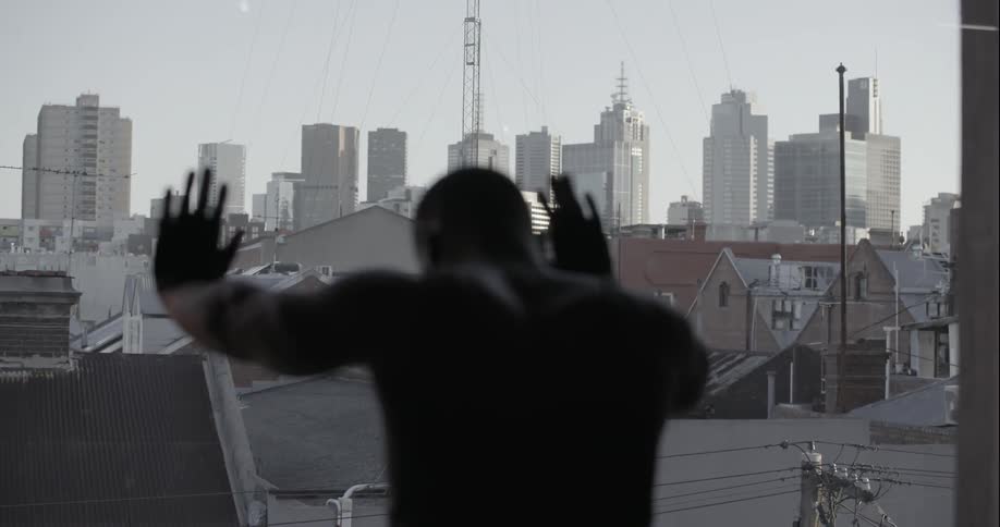 A man is leaning against a window with a city view