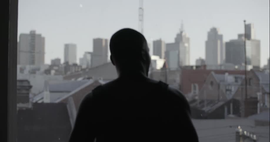 Man looks out the window at a large city