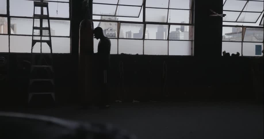 A man is punching a bag in a dark gym
