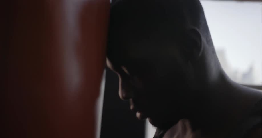A man is punching a heavy bag then rests
