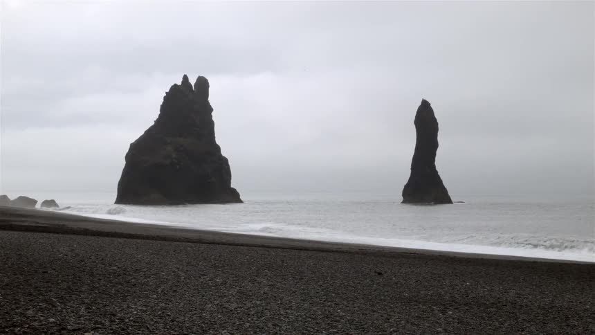Tall rock formations protruding through the waters on a beach