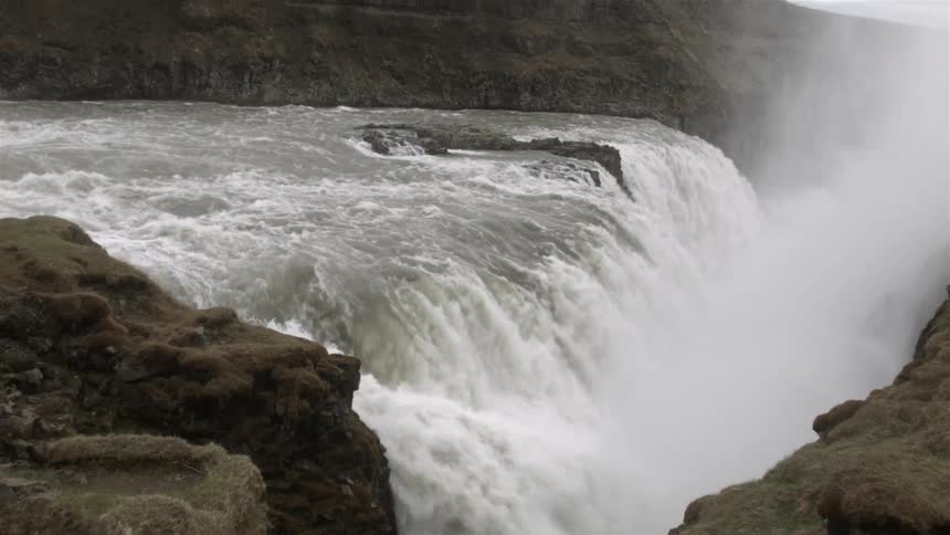 The water is rushing off this large waterfall