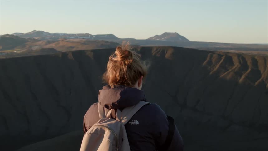 A woman is on the top of a mountain taking photographs
