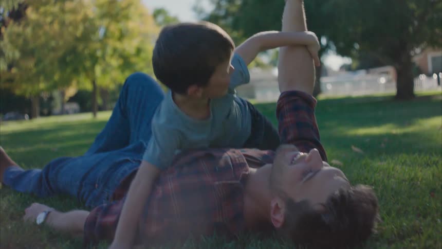 A father and son play with a football in the yard