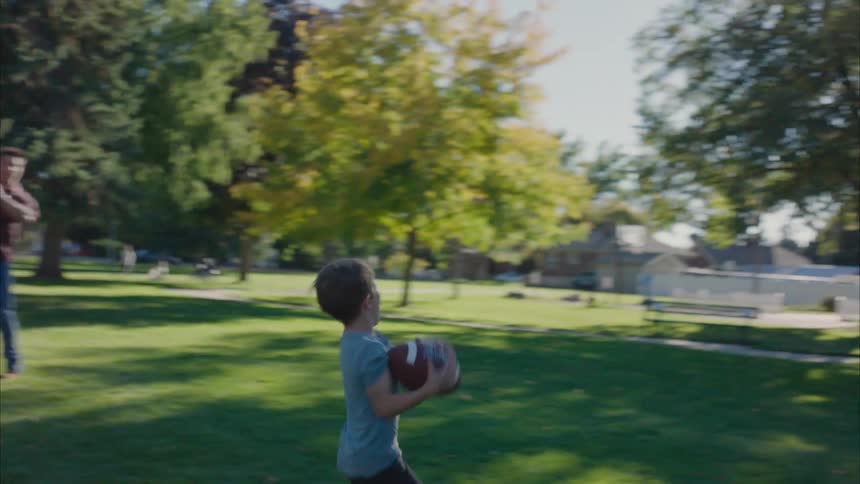 A little boy playing american football with a little girl and their father