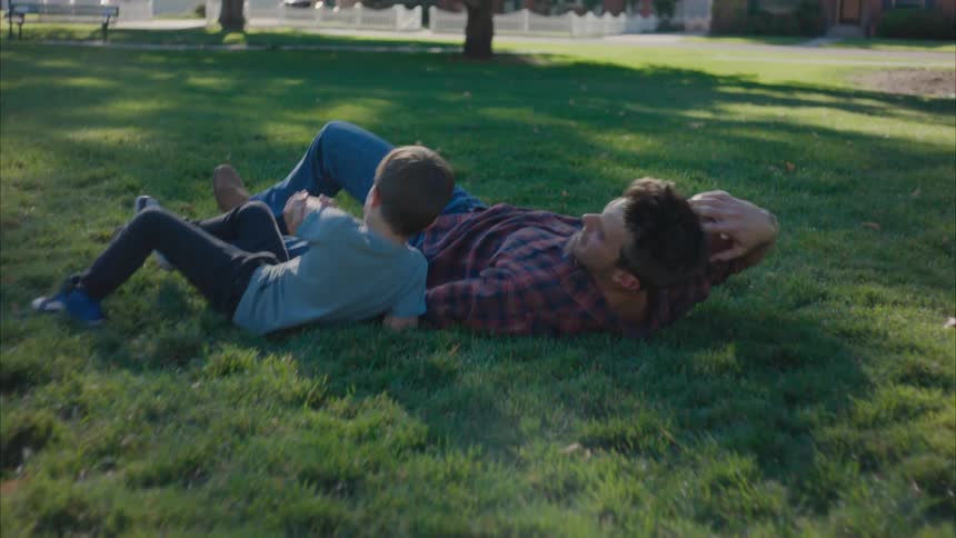 Father and son plays with a ball in the park at midday