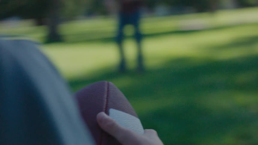 Closeup of a boys hands holding an american football and squeezing it