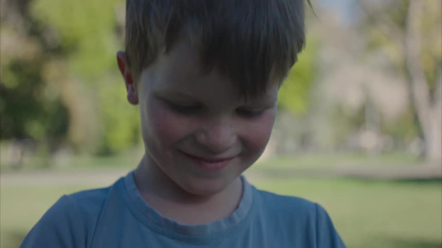 A smiling little boy in a park on a sunny day