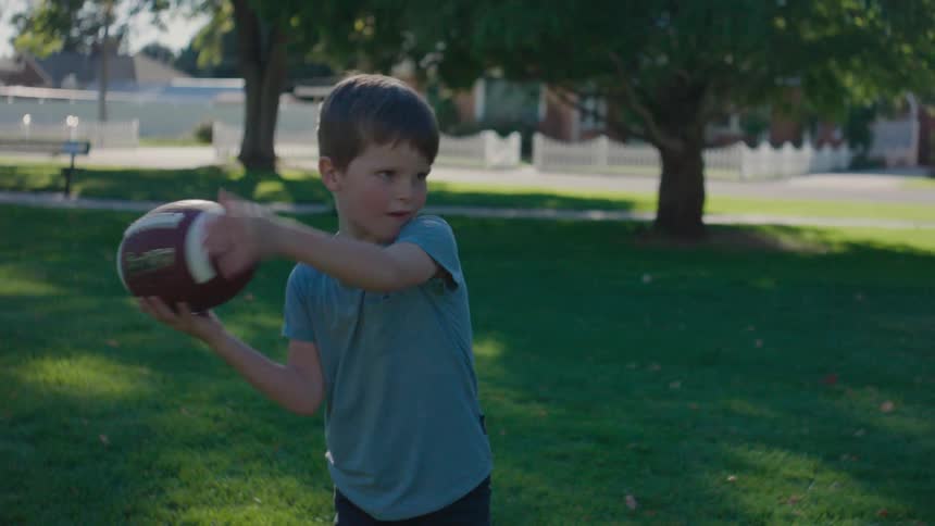 A boy throwing a ball in a park during the day