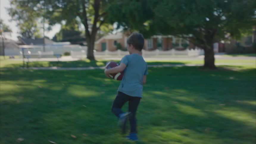 A father and son are playing football in the park