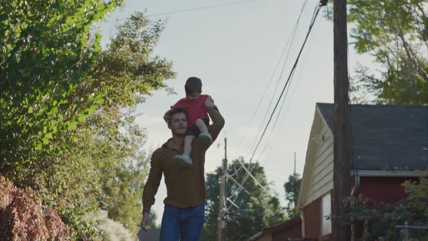 A man puts his son on his shoulder and the son strokes his head