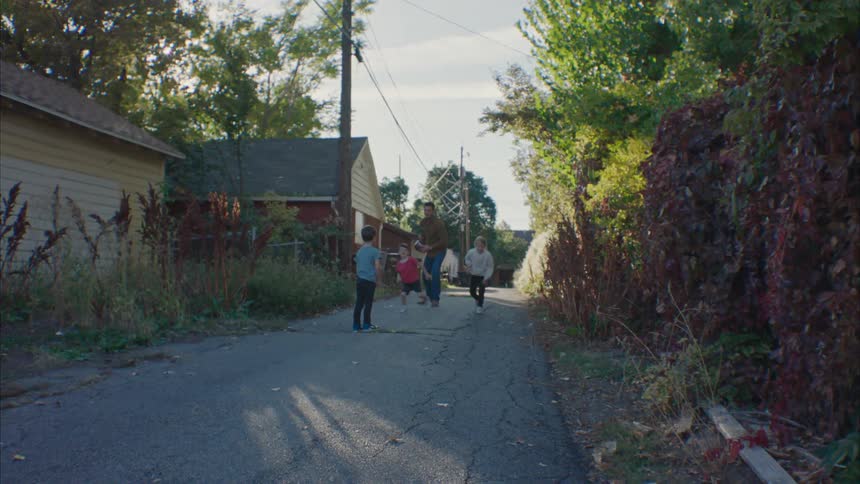 Father plays football with his kids in the street at morning
