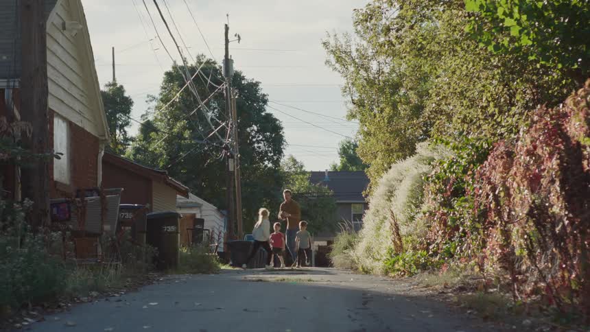 Father and three children playing american football on the street on a sunny day