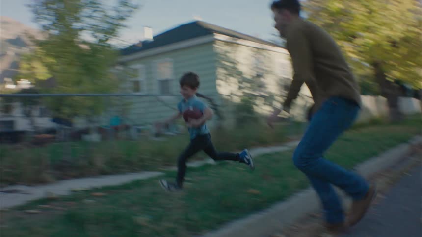 Father plays football with his kids in the street at morning