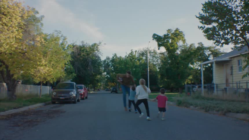 Father playing with his children in the middle of a street in a residential neighborhood