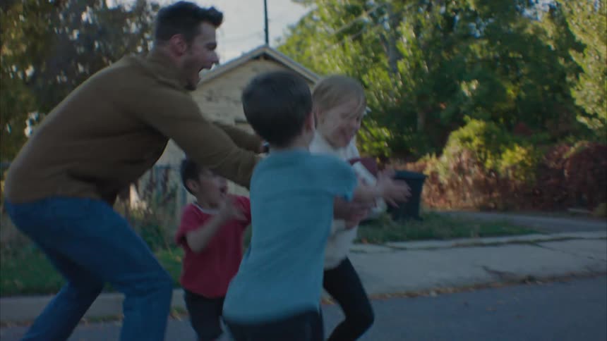 Father plays football with his kids in the street at morning