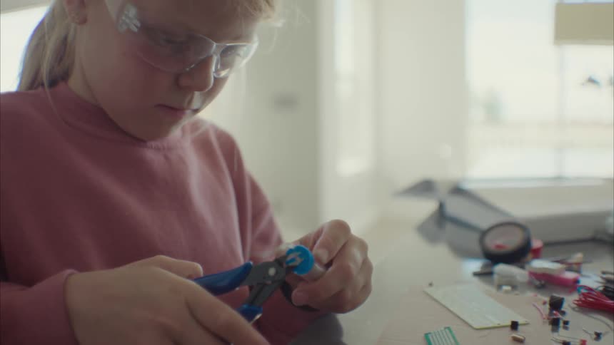 A young child is building a science project while wearing googles