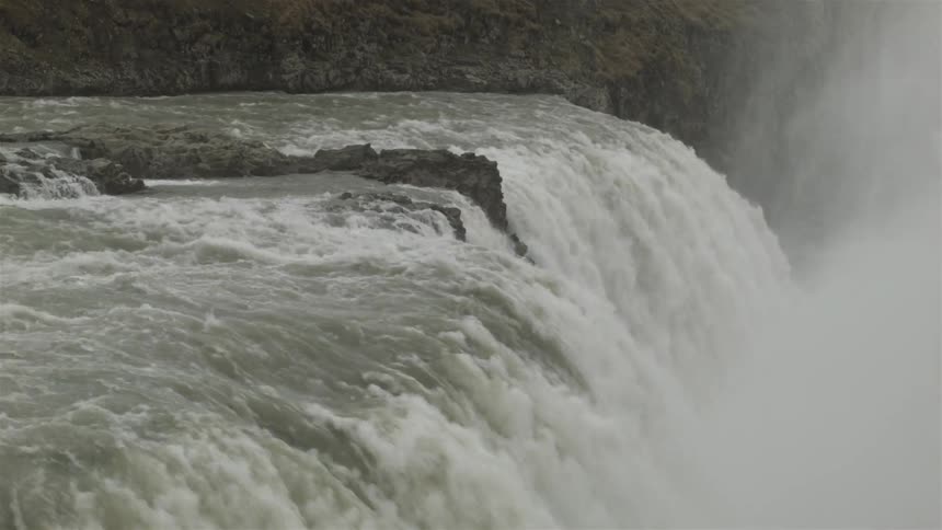 Water rushes off the top of a large waterfall