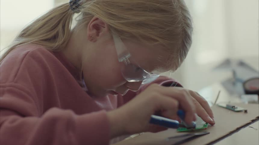 A girl repairing electronic parts in a laboratory
