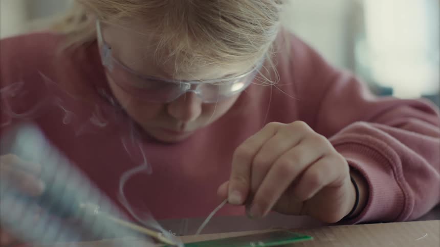 Blonde girl solders small circuit board