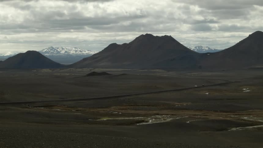 Vehicles travel on the road towards mountains in the distance