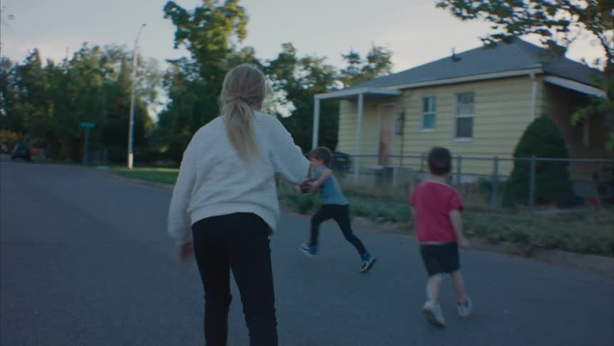 Father plays football with his kids in the street at morning