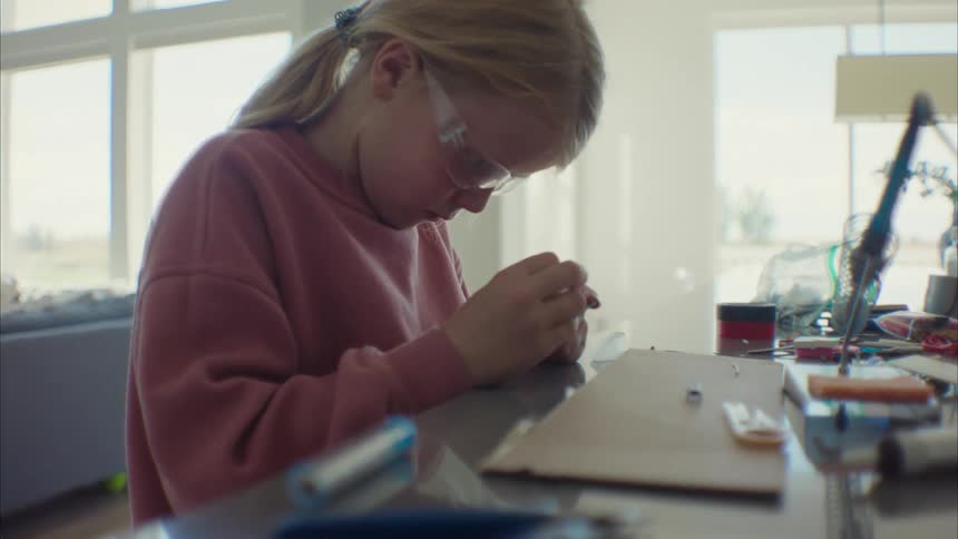 Girl sitting at a table and analyzing a piece of hardware