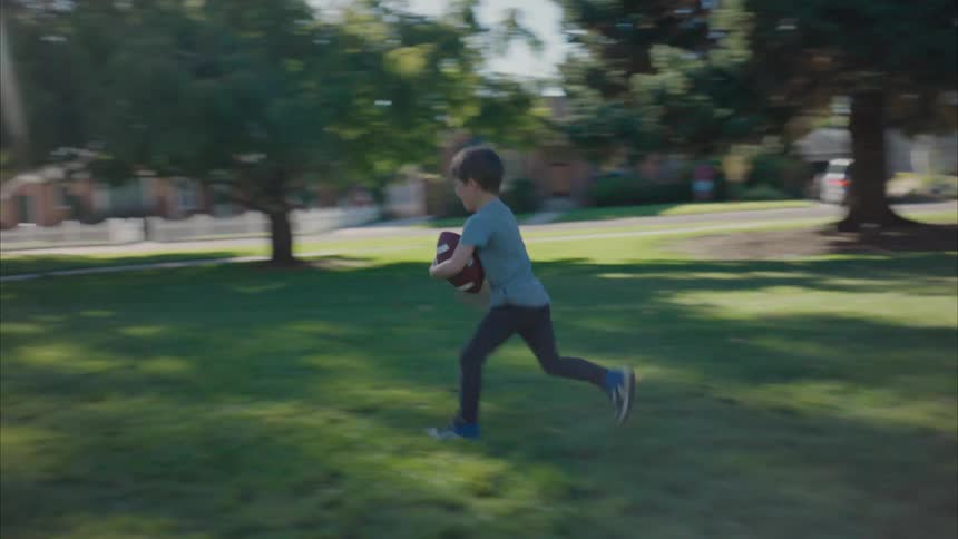 A little boy playing with his father with a ball and running