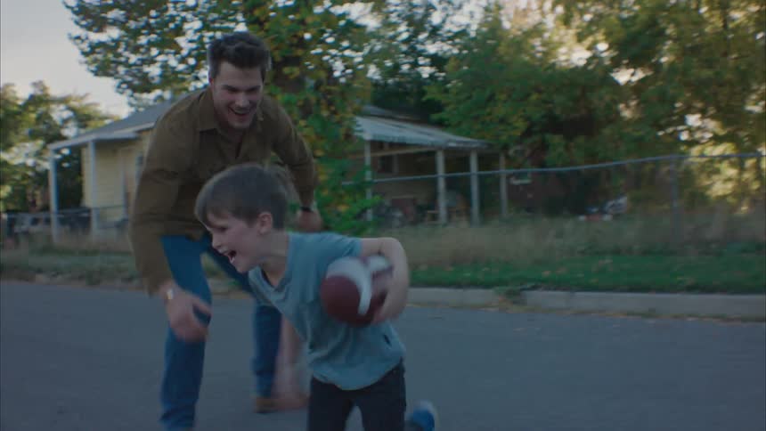 Father playing football with his son in the street