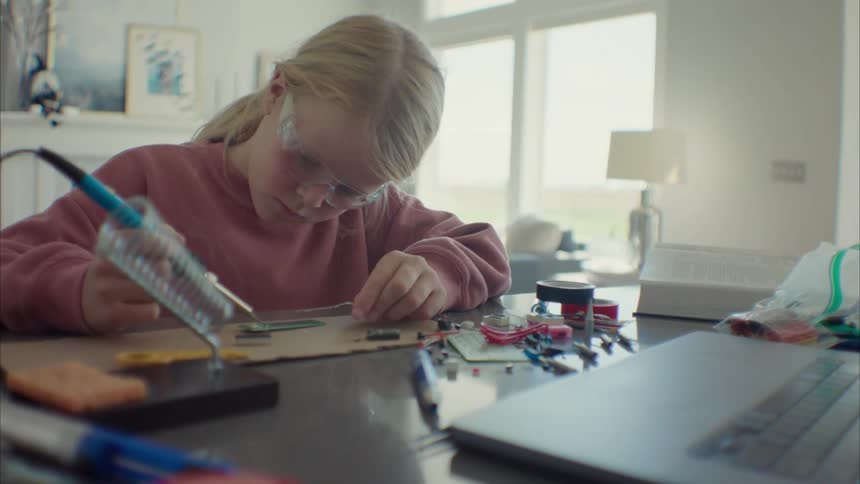 Girl wearing protective goggles working on electronics