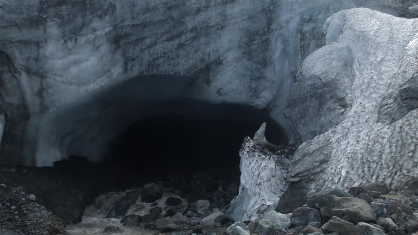 Water pours out from the opening of a cave