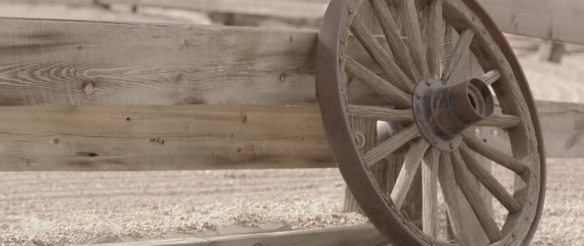 A wooden carriage wheel placed on a wooden fence