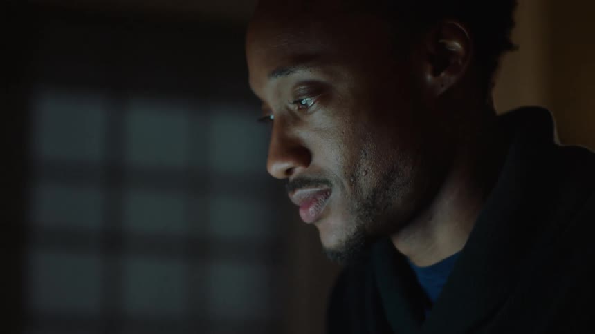 Man smiles while typing on a laptop indoor at night