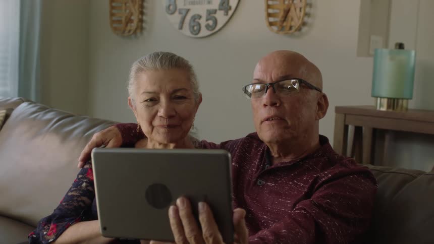Portrait of elderly individuals having a conversation with someone via a tablet