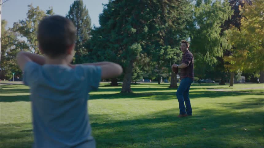 A little boy throwing an american football to his father