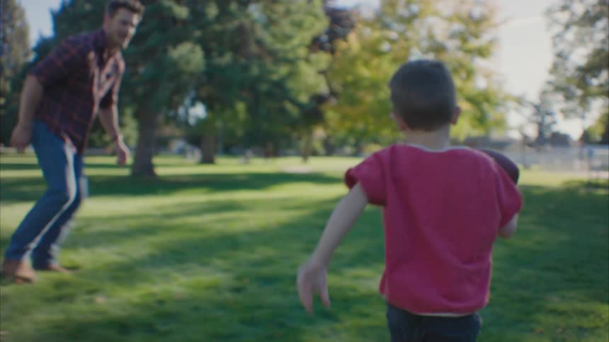 Father playing football with his sons in the park