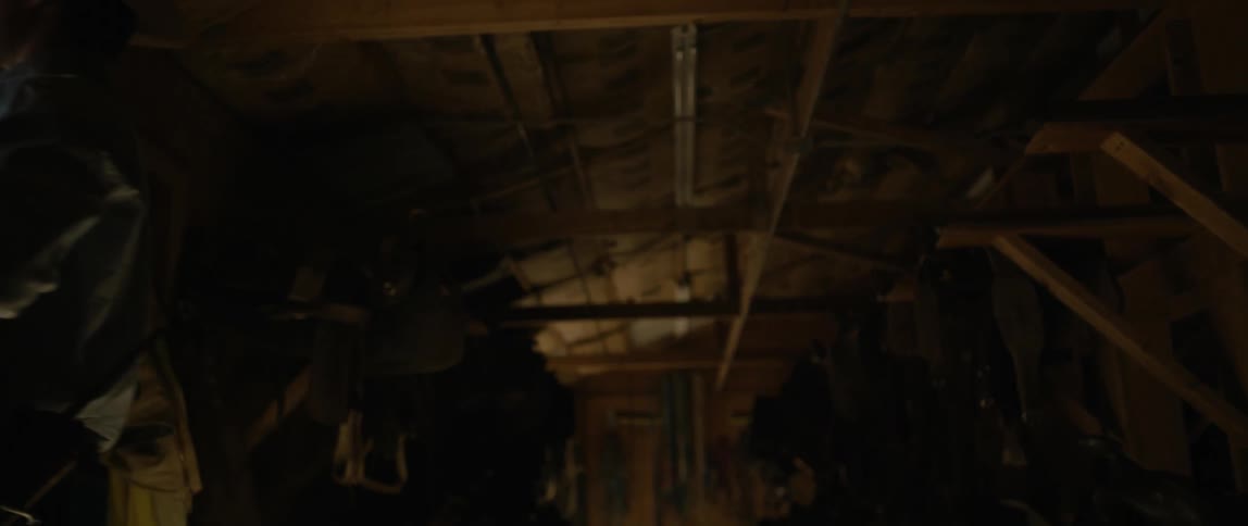 Cowboy takes a saddle out of the barn